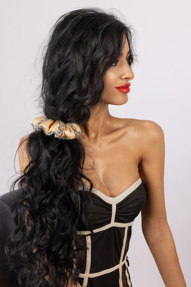 A black-haired girl with a ponytail is wearing beige Malkiele designer silk scrunchie with Swarovski pearls