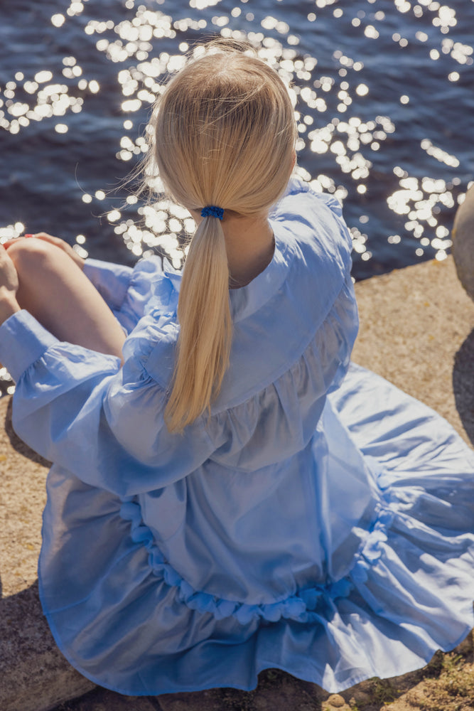 A blonde-haired girl from behind is wearing blue Malkiele designer silk gentle scrunchie