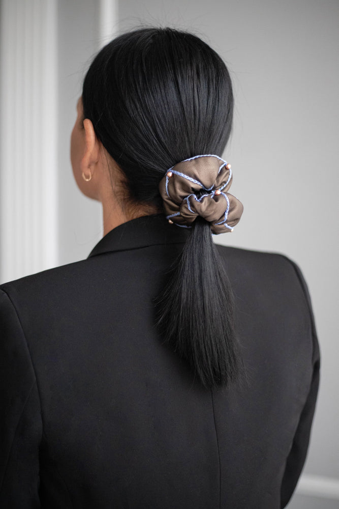 A black-haired girl with a ponytail is wearing brown Malkiele designer vegan leather scrunchie