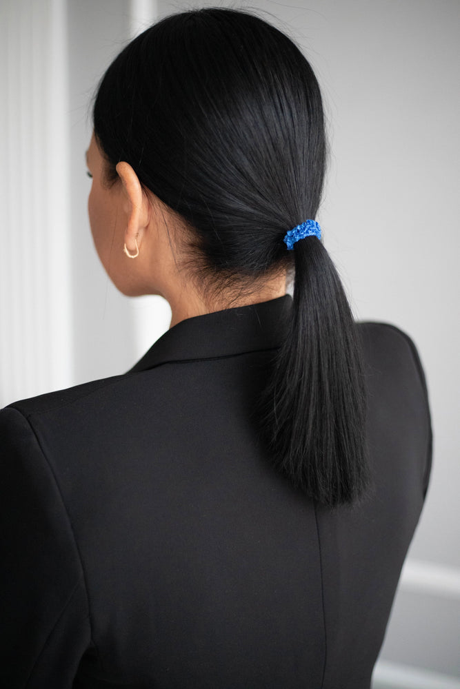 A black-haired girl with a ponytail is wearing blue Malkiele designer silk scrunchie