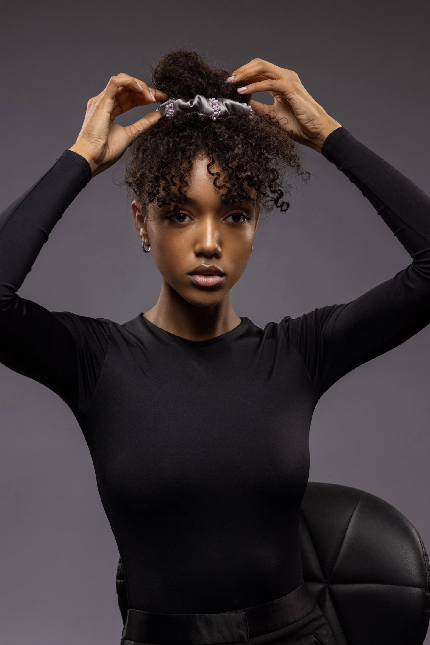 A dark skin girl with a top bun hairstyle is wearing grey Malkiele designer silk scrunchie