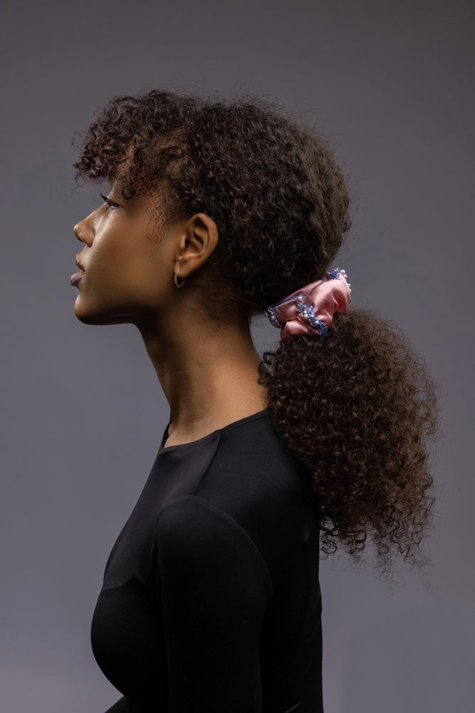 A dark skin girl with a ponytail is wearing pink Malkiele designer silk scrunchie