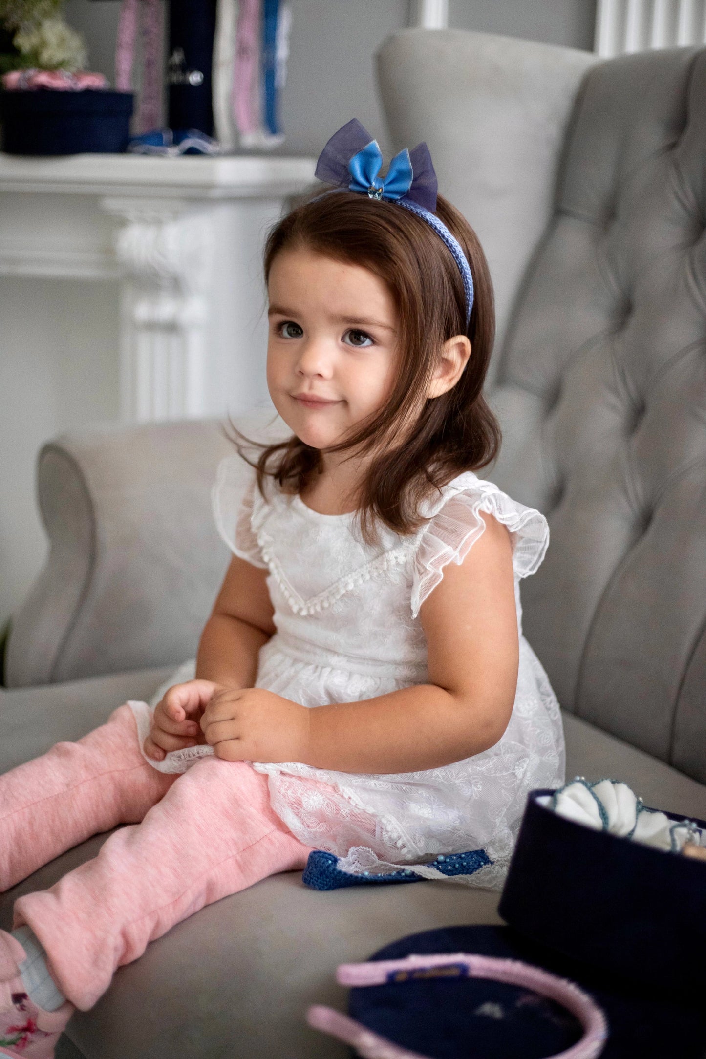 A little girl is wearing light blue Malkiele designer silk knit headband with leather bow