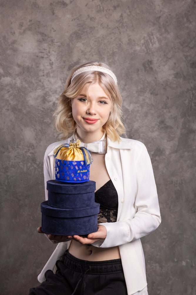 Happy smiling girl is wearing white silk knit headbands and holds blue velvet boxes by Malkiele sustainable designer