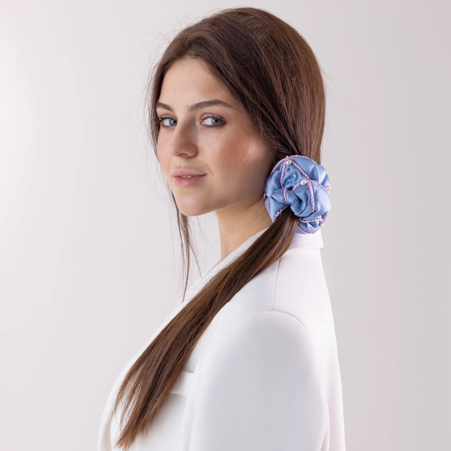 Dark-haired smiling girl with stylish ponytail is wearing light blue silk scrunchie, embellished with pearls from Swarovski® by Malkiele sustainable designer.