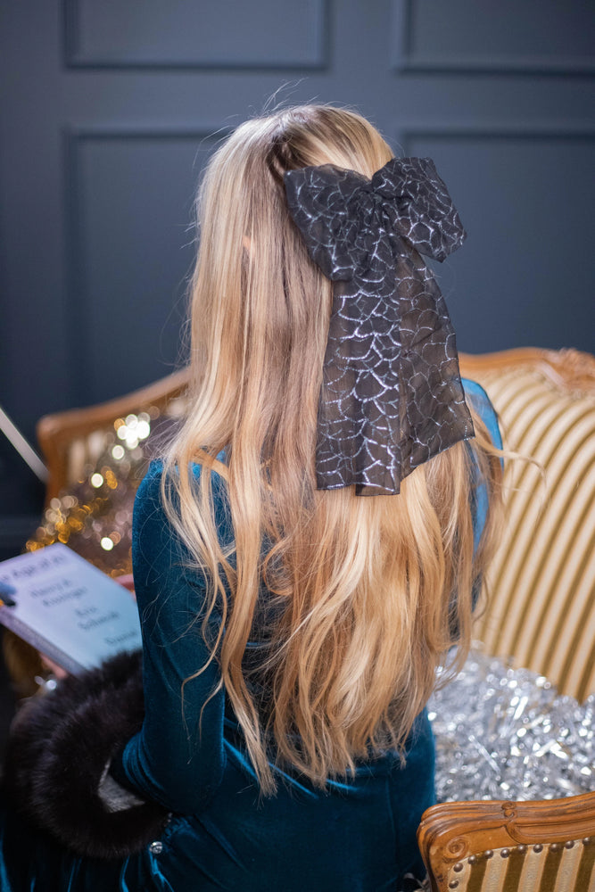 A blonde-haired girl is wearing black Malkiele designer chiffon art bow