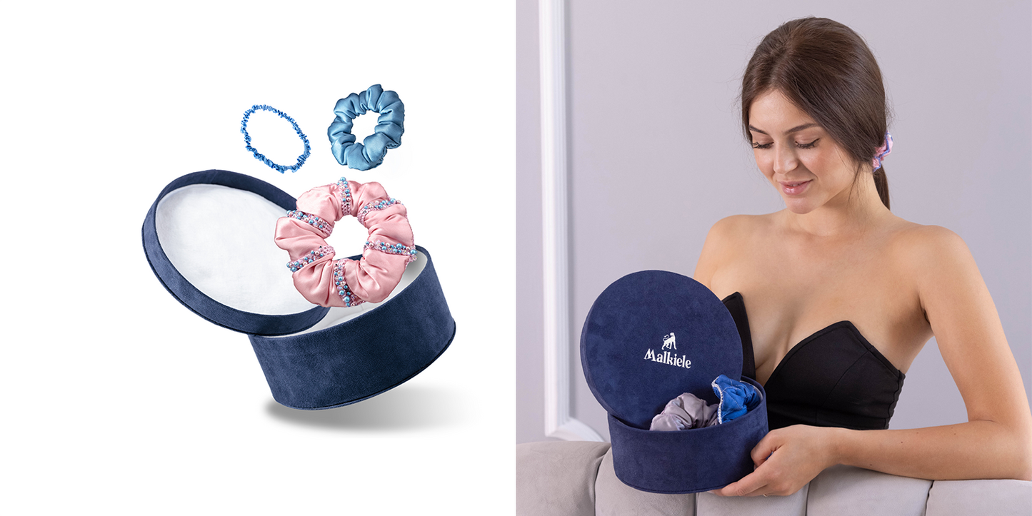 Smiling woman is holding a gift set box in blue with silk hair accessories, Malkiele designer.