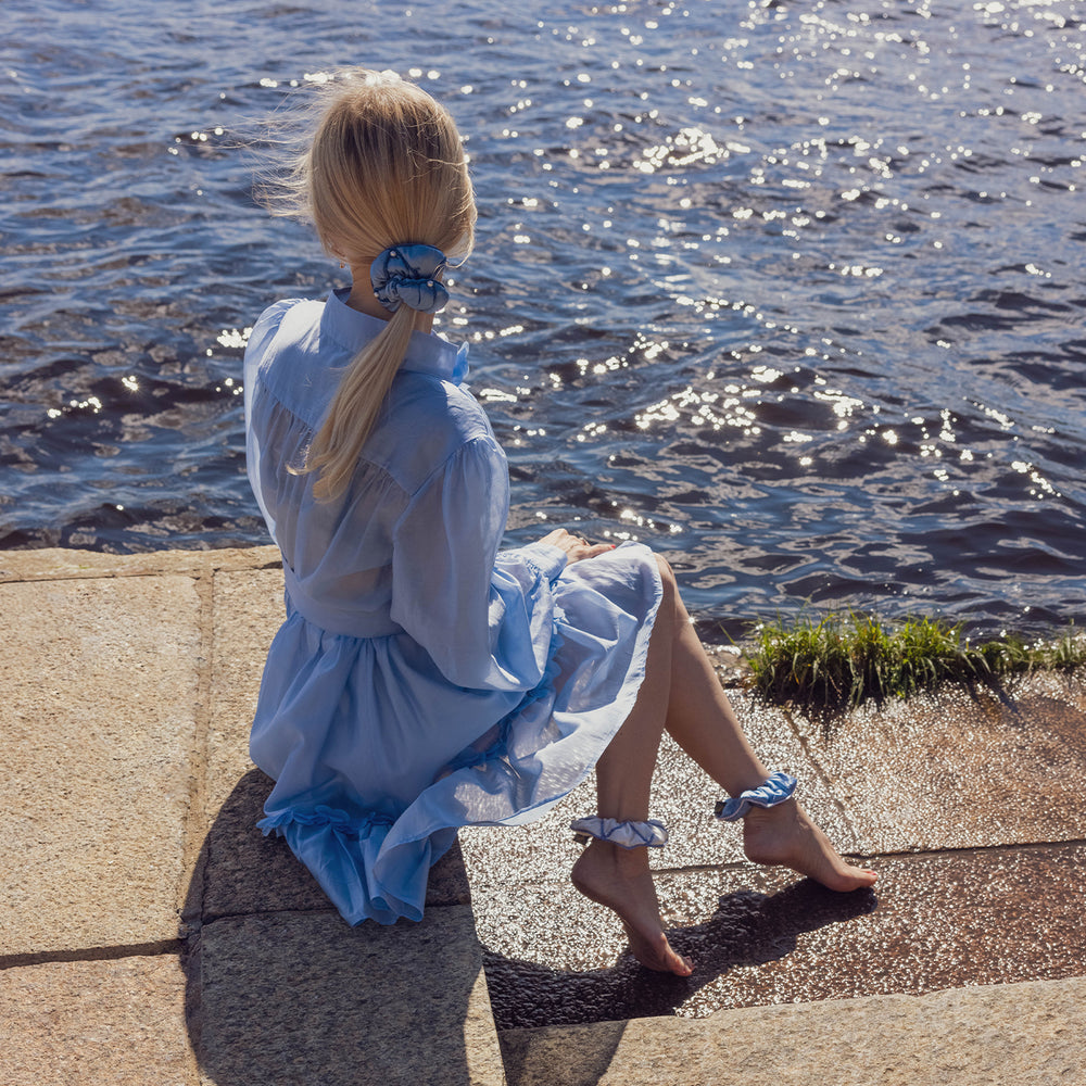 Sophisticated blonde-haired girl in light blue dress is wearing Malkiele designer Majestic 6 Pearls silk scrunchie, stylish ponytail.