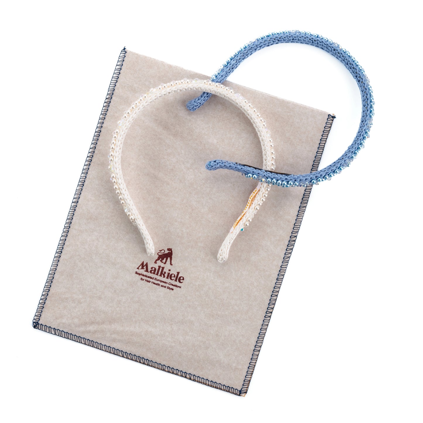 Two silk knit headbands are placed on Malkiele Signature paper packaging.