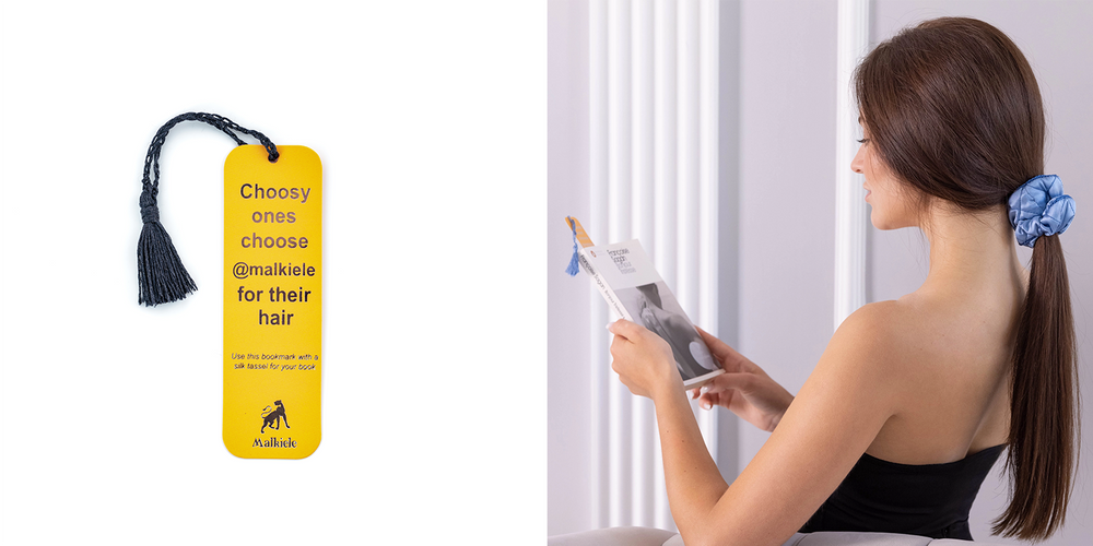 A dark-haired girl is holding a book with Malkiele designer bookmark with silk tassel in yellow.