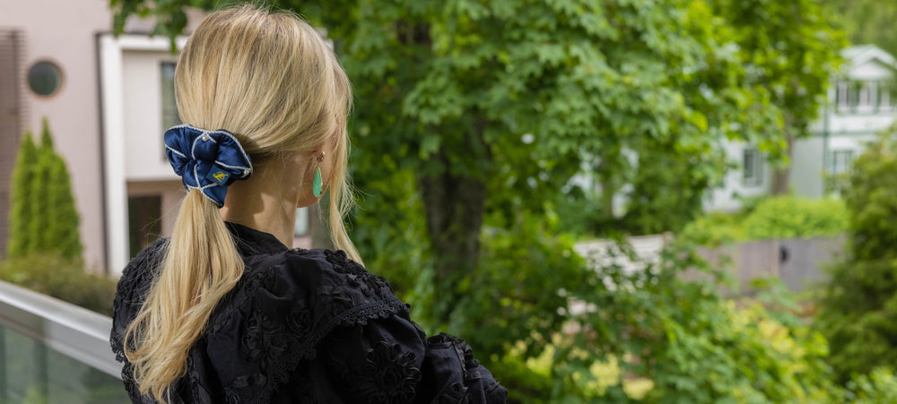 Sophisticated blond girl with stylish ponytail in black dress is wearing Malkiele designer silk scrunchie Majestic 6 pearls from Swarovski®, in blue color.