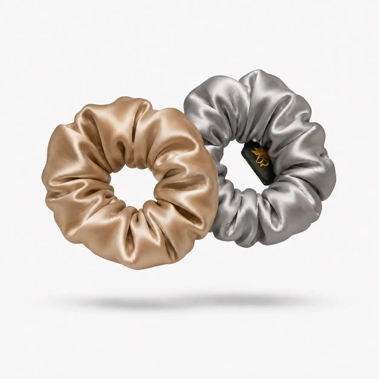 
                  
                    Two satin scrunchies, one gold and one silver, on a light gray background.
                  
                