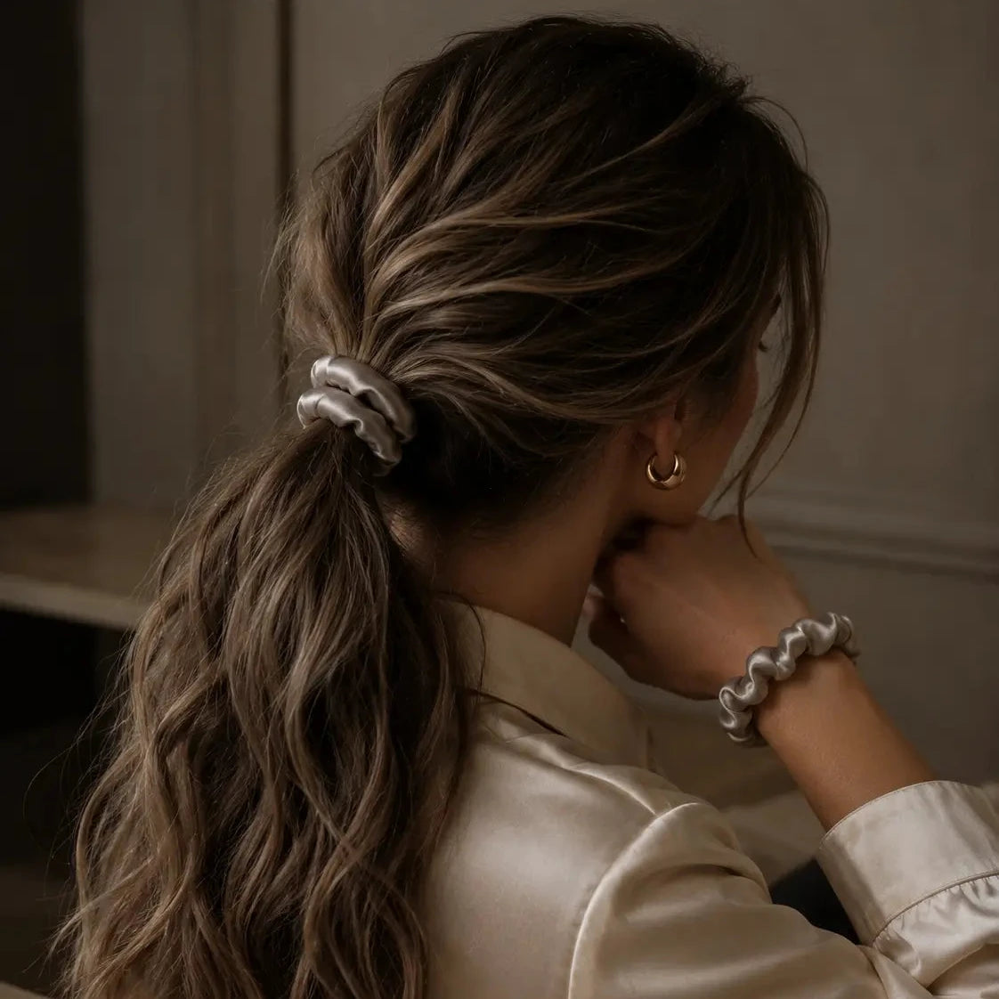 
                  
                    Woman with styled hair and accessories in a neutral setting
                  
                