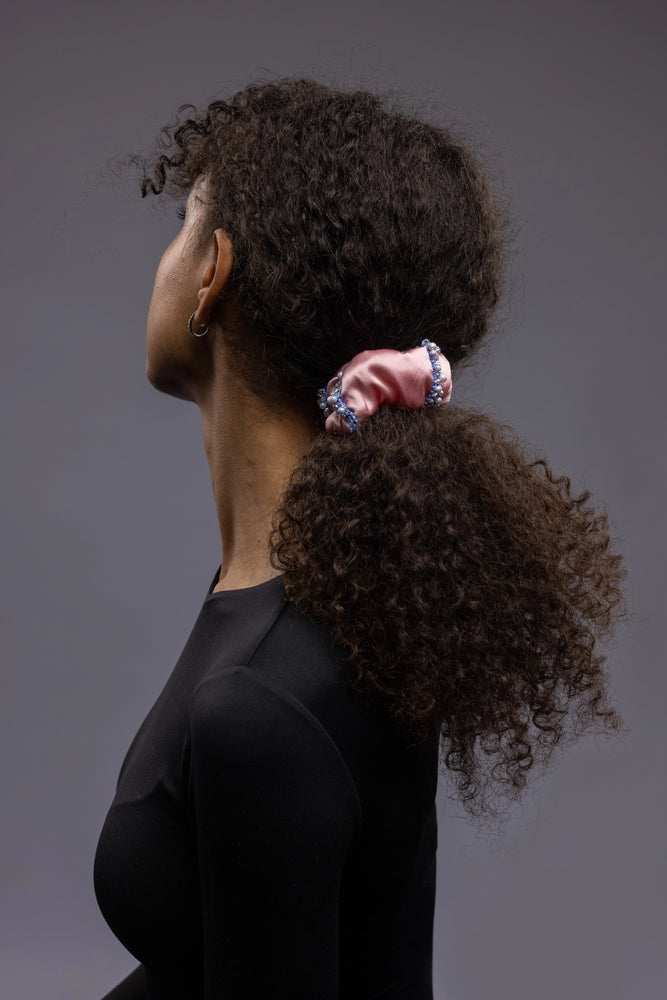 
                  
                    A dark-haired girl with stylish ponytail is wearing Malkiele designer pink silk scrunchie, embellished with crystals from Swarovski and light blue silk knit ribbon, name Elizabeth.
                  
                