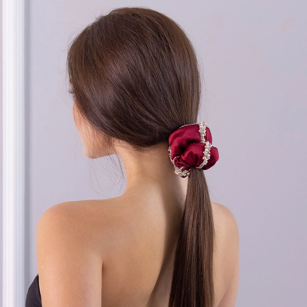 
                  
                    A dark-haired girl, view from the back, with stylish ponytail is wearing Malkiele designer burgundy silk scrunchie, embellished with crystals from Swarovski® and beige silk knit ribbon, name Elizabeth.
                  
                