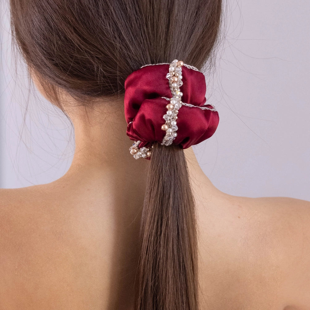 
                  
                    A dark-haired girl, view from the back, with stylish ponytail is wearing Malkiele designer burgundy silk scrunchie, embellished with crystals from Swarovski® and beige silk knit ribbon, name Elizabeth.
                  
                