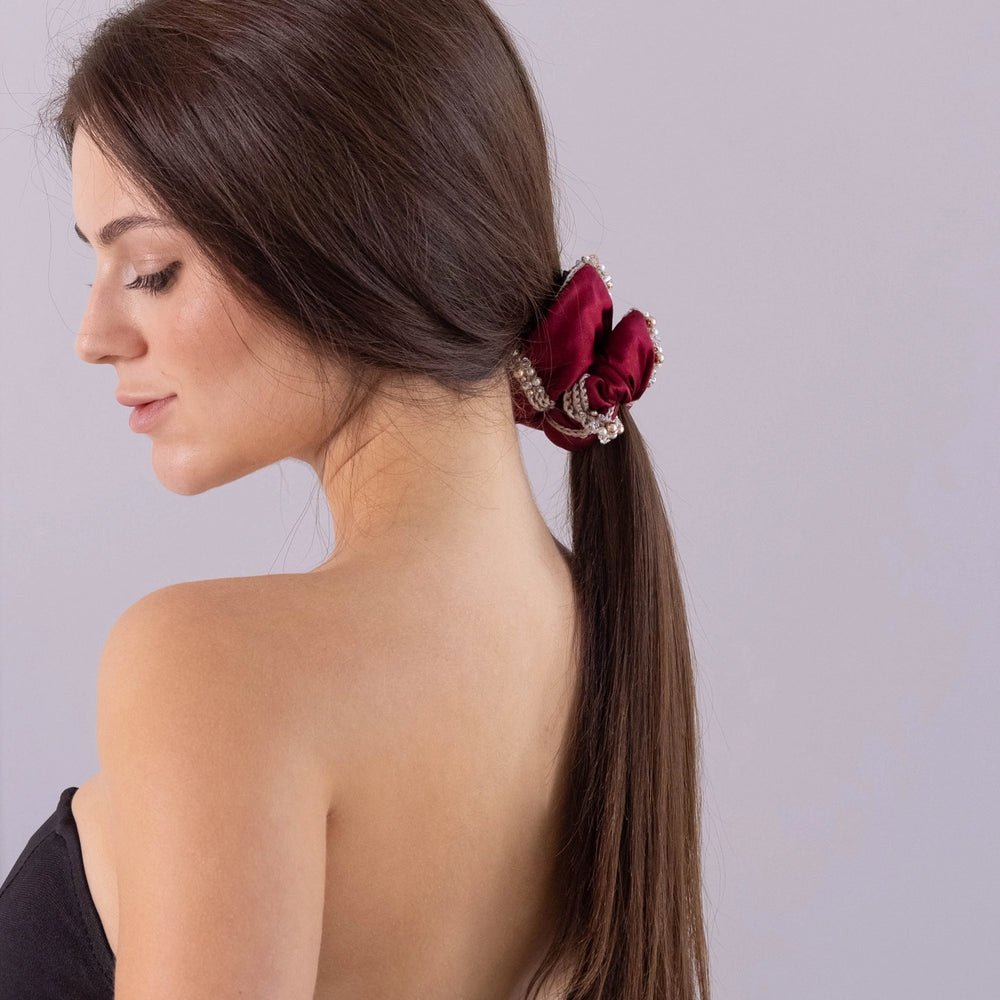 
                  
                    A dark-haired girl, half the face, with stylish ponytail is wearing Malkiele designer burgundy silk scrunchie, embellished with crystals from Swarovski® and beige silk knit ribbon, name Elizabeth.
                  
                