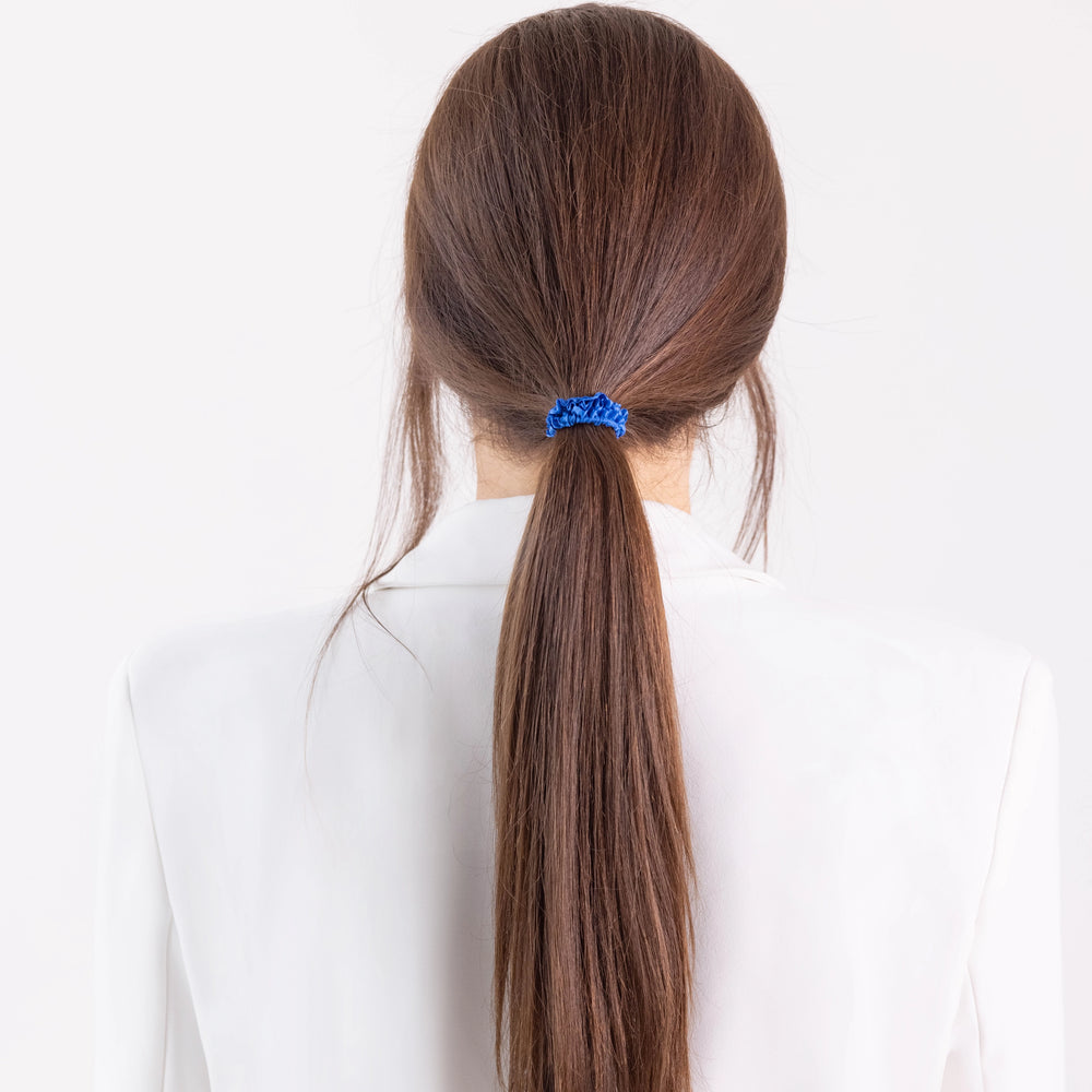 
                  
                    A dark-haired girl in white jacket, view from the back, with classic ponytail is wearing Malkiele designer royal blue silk gentle hair tie, name Finesse.
                  
                