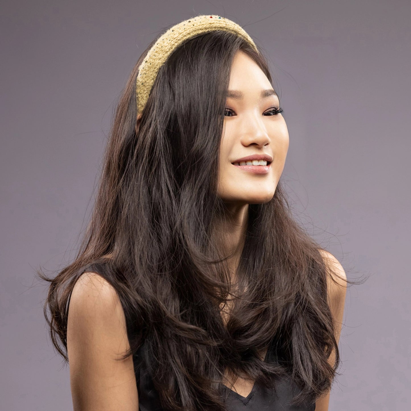 
                  
                    A dark-haired Asian woman is wearing Malkiele silk knit headband in yellow, name Lofty
                  
                