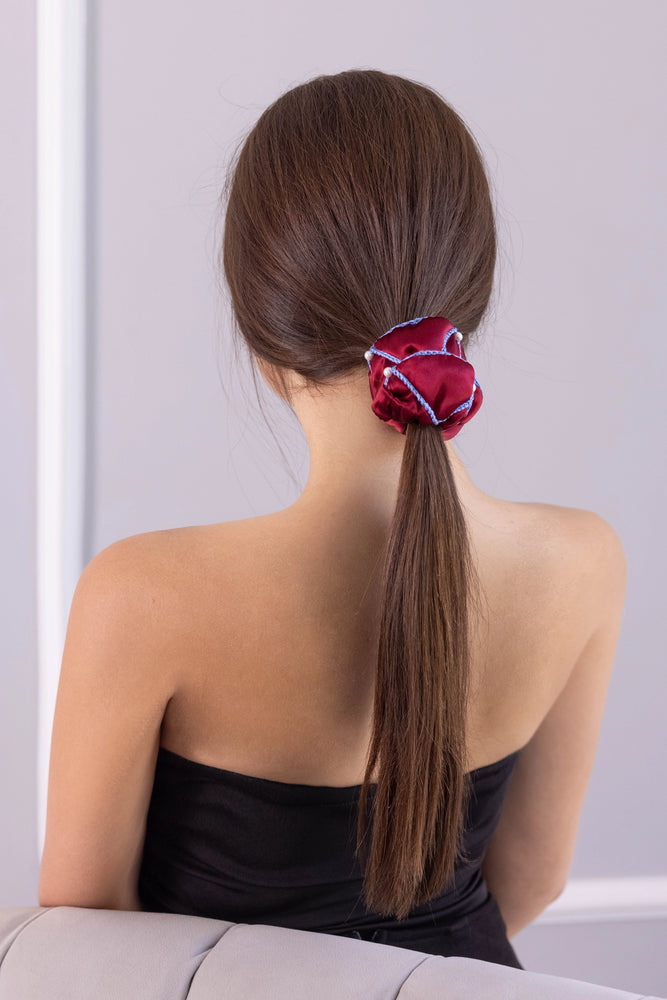 
                  
                    A dark-haired woman, view from the back, with stylish ponytail is wearing Malkiele designer burgundy silk scrunchie, embellished with 6 white pearls from Swarovski and light blue silk knit ribbon, name Majestic.
                  
                