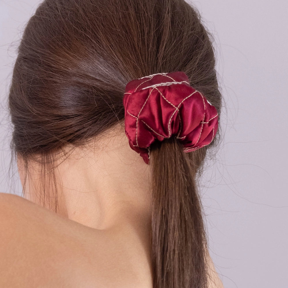 
                  
                    A dark-haired woman, view from the back, with stylish ponytail is wearing Malkiele designer burgundy silk scrunchie, embellished beige silk knit ribbon, name Morning Passion.
                  
                