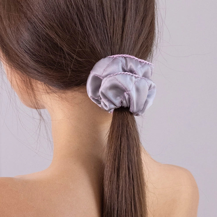 
                  
                    A dark-haired woman, view from the back, with stylish ponytail is wearing Malkiele designer grey silk scrunchie, embellished pink silk knit ribbon, name Morning Passion.
                  
                