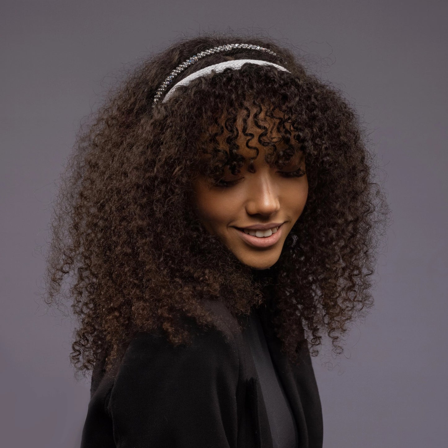 
                  
                    A dark-haired smiling girl is wearing Malkiele designer grey silk knit headbands, one is embellished with light blue pearls from Swarovski, name Perfect.
                  
                