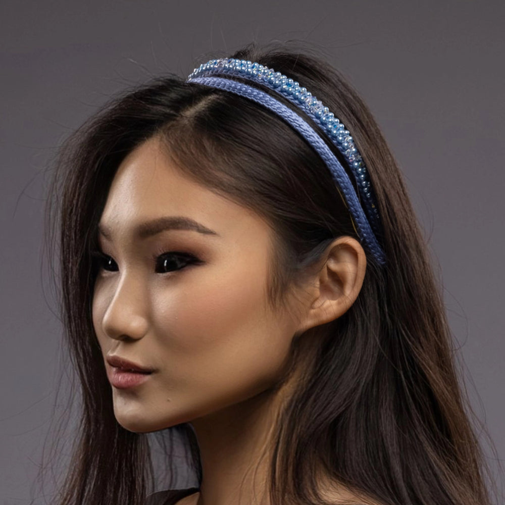 
                  
                    A dark-haired asian woman is wearing Malkiele designer silk headbands in light blue, name Victorious, details, side view
                  
                