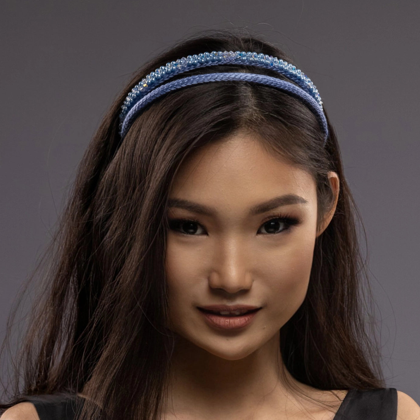 
                  
                    A dark-haired asian woman is wearing Malkiele designer silk headbands in light blue, name Victorious, details
                  
                