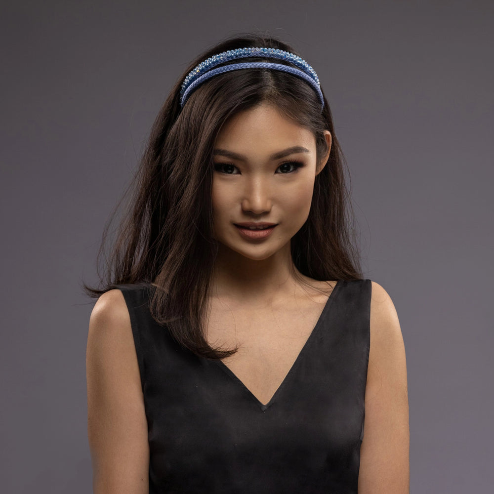 
                  
                    A dark-haired asian woman is wearing Malkiele designer silk headbands in light blue, name Victorious, front view
                  
                