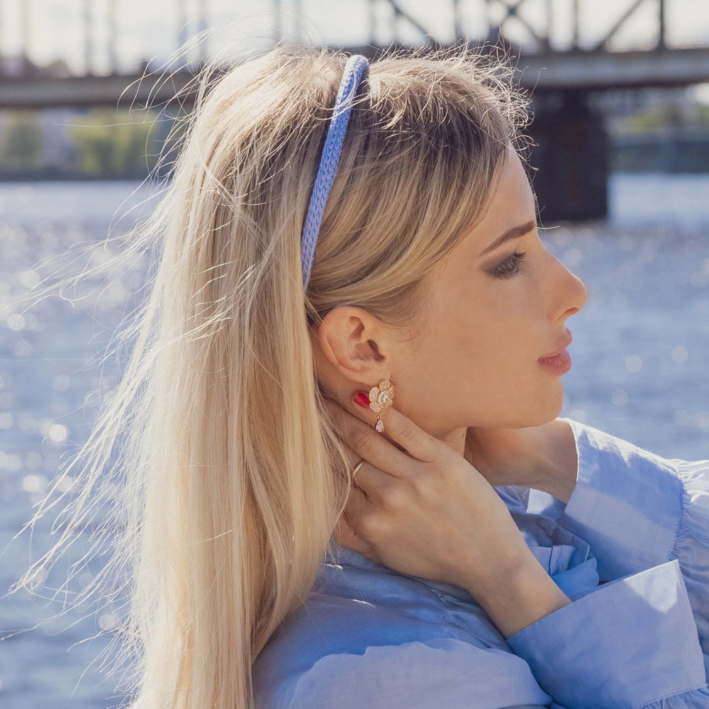 A blonde-haired girl in light blue dress, side view, is wearing Malkiele designer light blue silk knit headband, name Virgin.