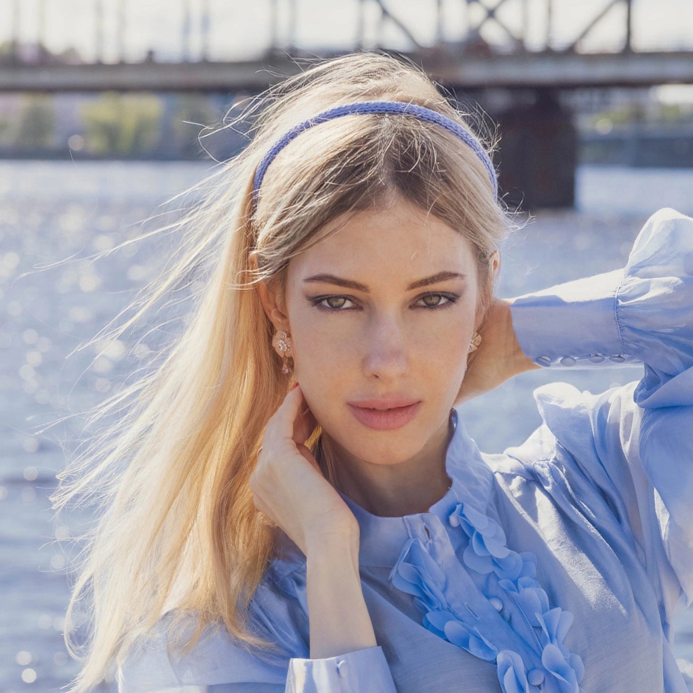 
                  
                    A blonde-haired girl in light blue dress, front view, is wearing Malkiele designer light blue silk knit headband, name Virgin.
                  
                