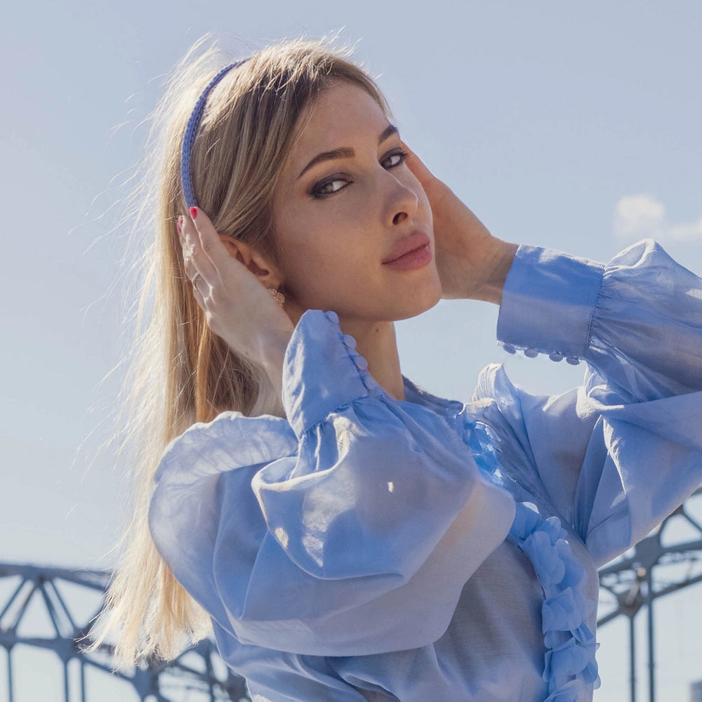 
                  
                    A blonde-haired girl in light blue dress, front view, is wearing Malkiele designer light blue silk knit headband, name Virgin.
                  
                