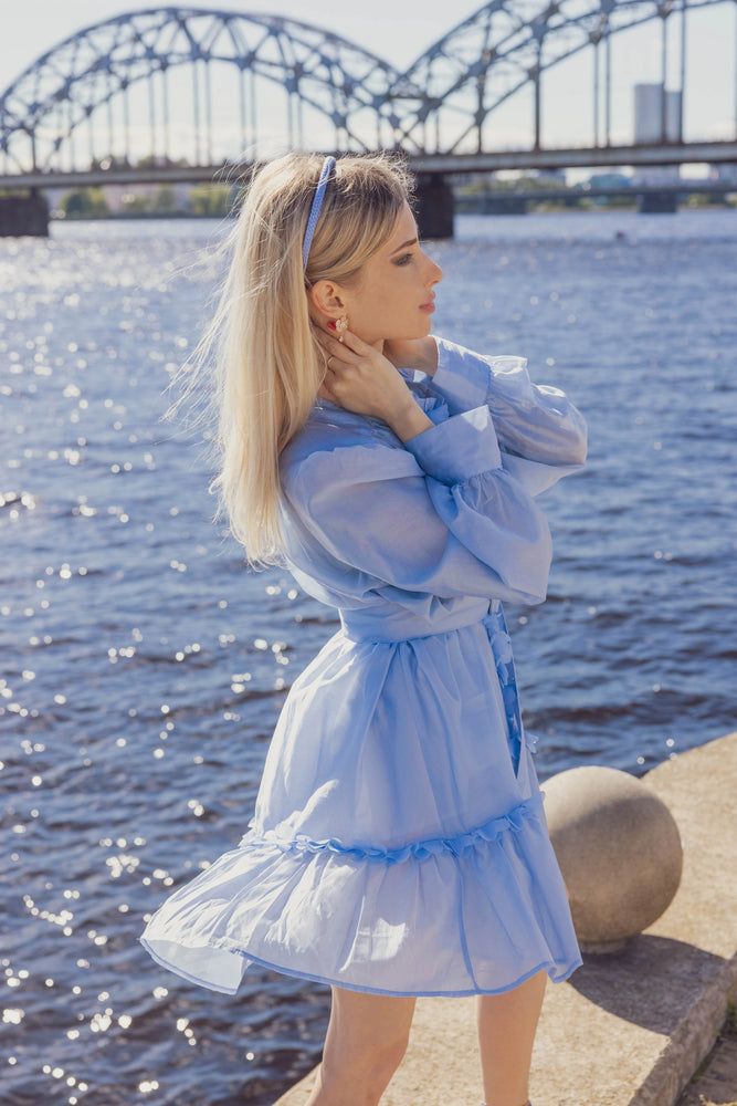 
                  
                    A blonde-haired girl in light blue dress, side view, is wearing Malkiele designer light blue silk knit headband, name Virgin.
                  
                