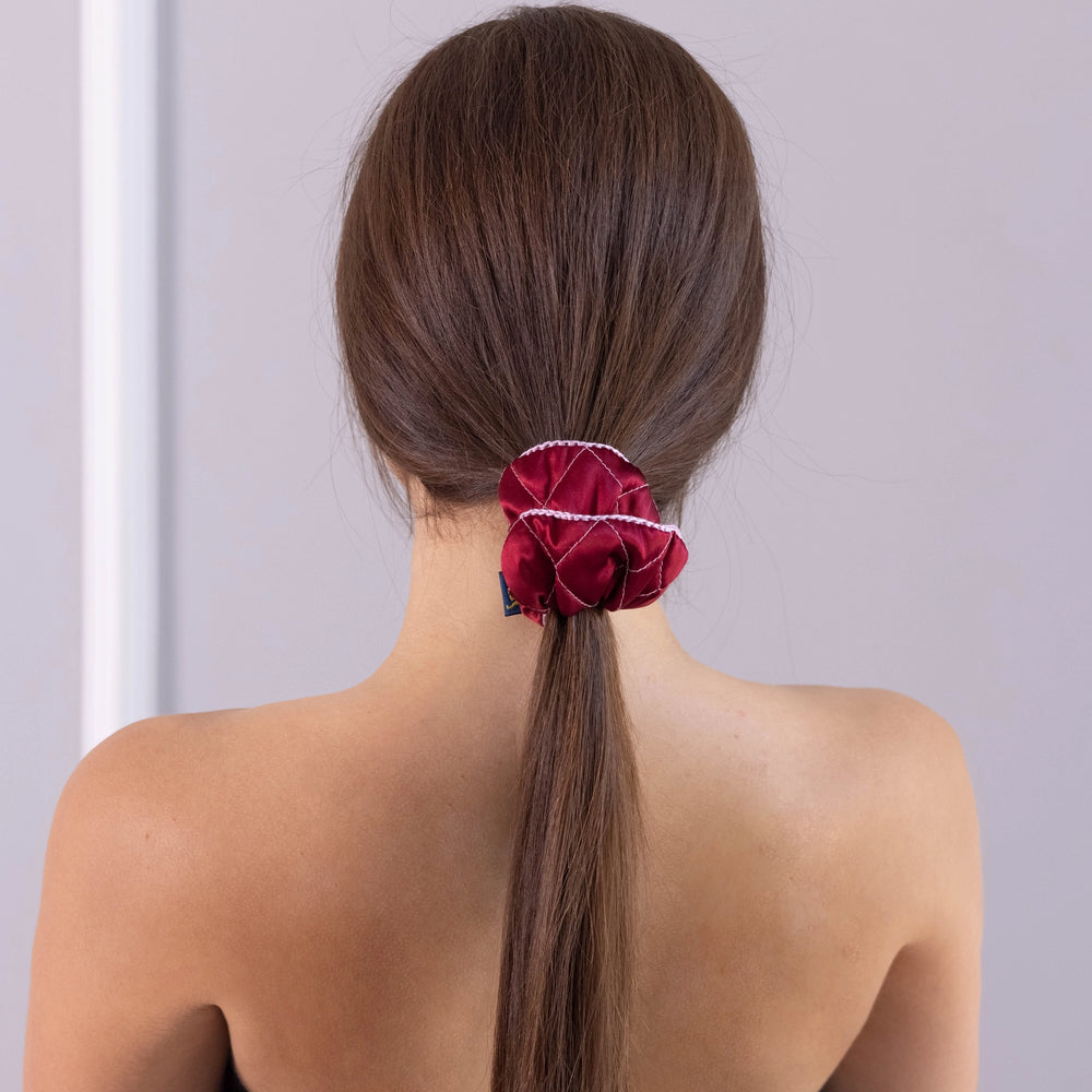 
                  
                    A dark-haired woman, view from the back, with stylish ponytail is wearing Malkiele designer burgundy silk scrunchie, embellished pink silk knit ribbon, name Morning Passion.
                  
                