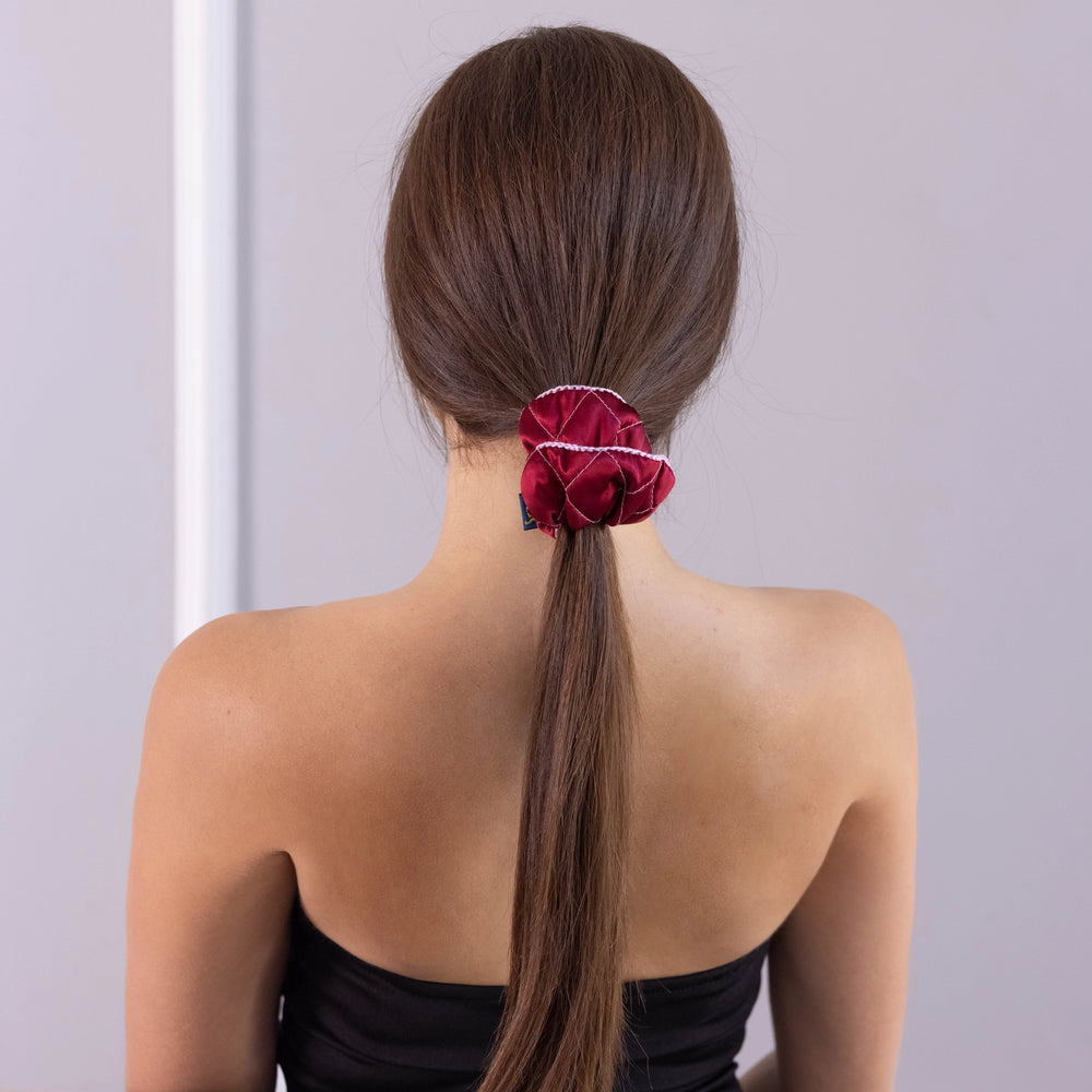 
                  
                    A dark-haired woman, view from the back, with stylish ponytail is wearing Malkiele designer burgundy silk scrunchie, embellished pink silk knit ribbon, name Morning Passion.
                  
                