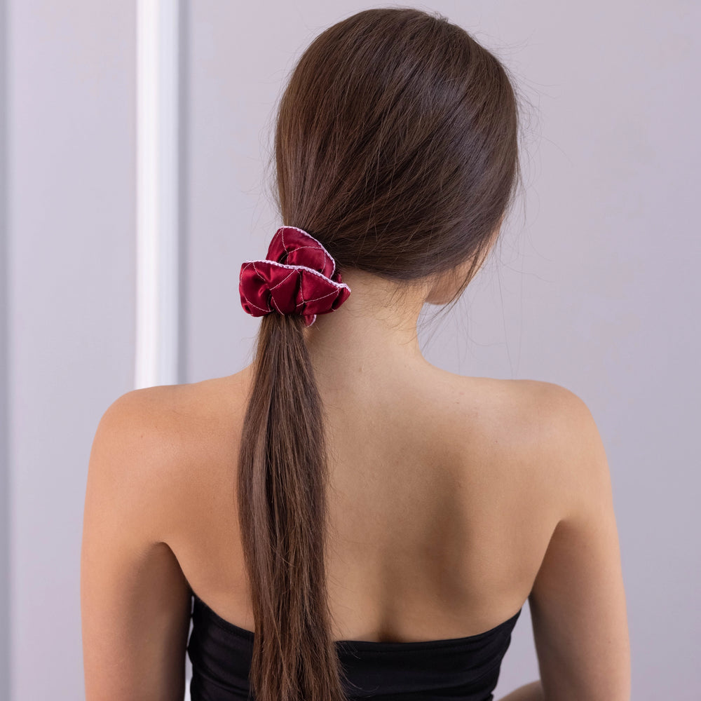 
                  
                    A dark-haired woman, view from the back, with stylish ponytail is wearing Malkiele designer burgundy silk scrunchie, embellished pink silk knit ribbon, name Morning Passion.
                  
                