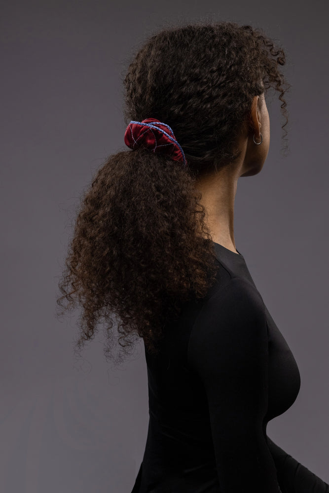 
                  
                    An African woman, view from the back, with stylish ponytail is wearing Malkiele designer burgundy quilted silk scrunchie, embellished with light blue silk knit ribbon, name Morning Passion
                  
                