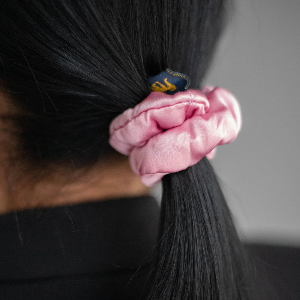 
                  
                    A black-haired woman, view from the back, with stylish ponytail is wearing Malkiele designer pink silk-covered coil scrunchie, name Grace.
                  
                