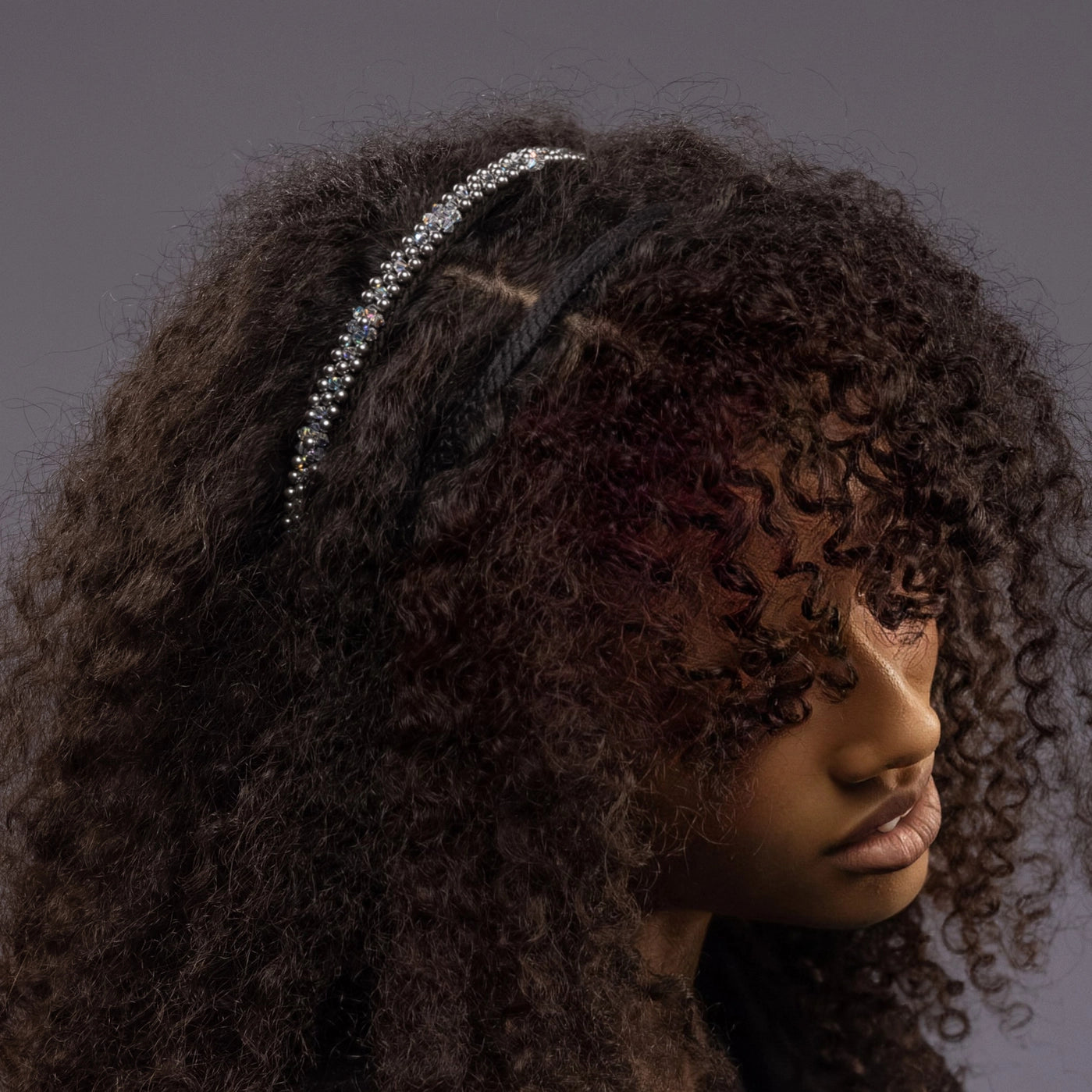 
                  
                    A dark-haired African woman is wearing Malkiele designer black silk knit headbands, embellished with pearls from Swarovski, name Victorious.
                  
                