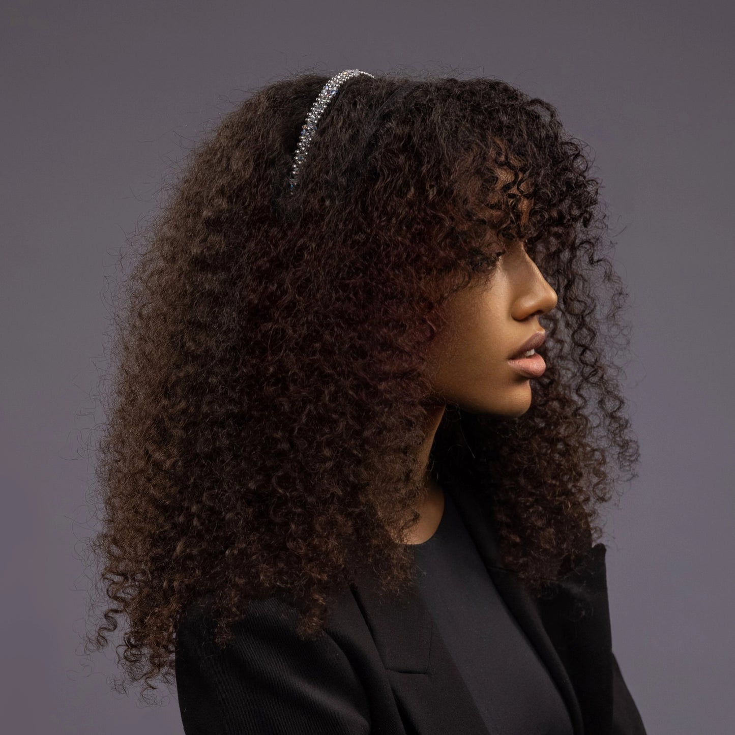 
                  
                    A dark-haired African woman is wearing Malkiele designer black silk knit headbands, embellished with pearls from Swarovski, name Victorious.
                  
                