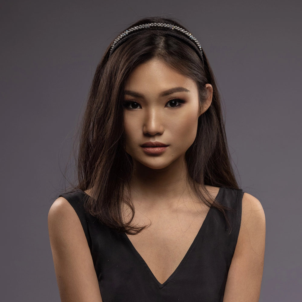 A dark-haired Asian girl is wearing Malkiele designer black silk knit headbands, embellished with pearls from Swarovski, name Victorious.