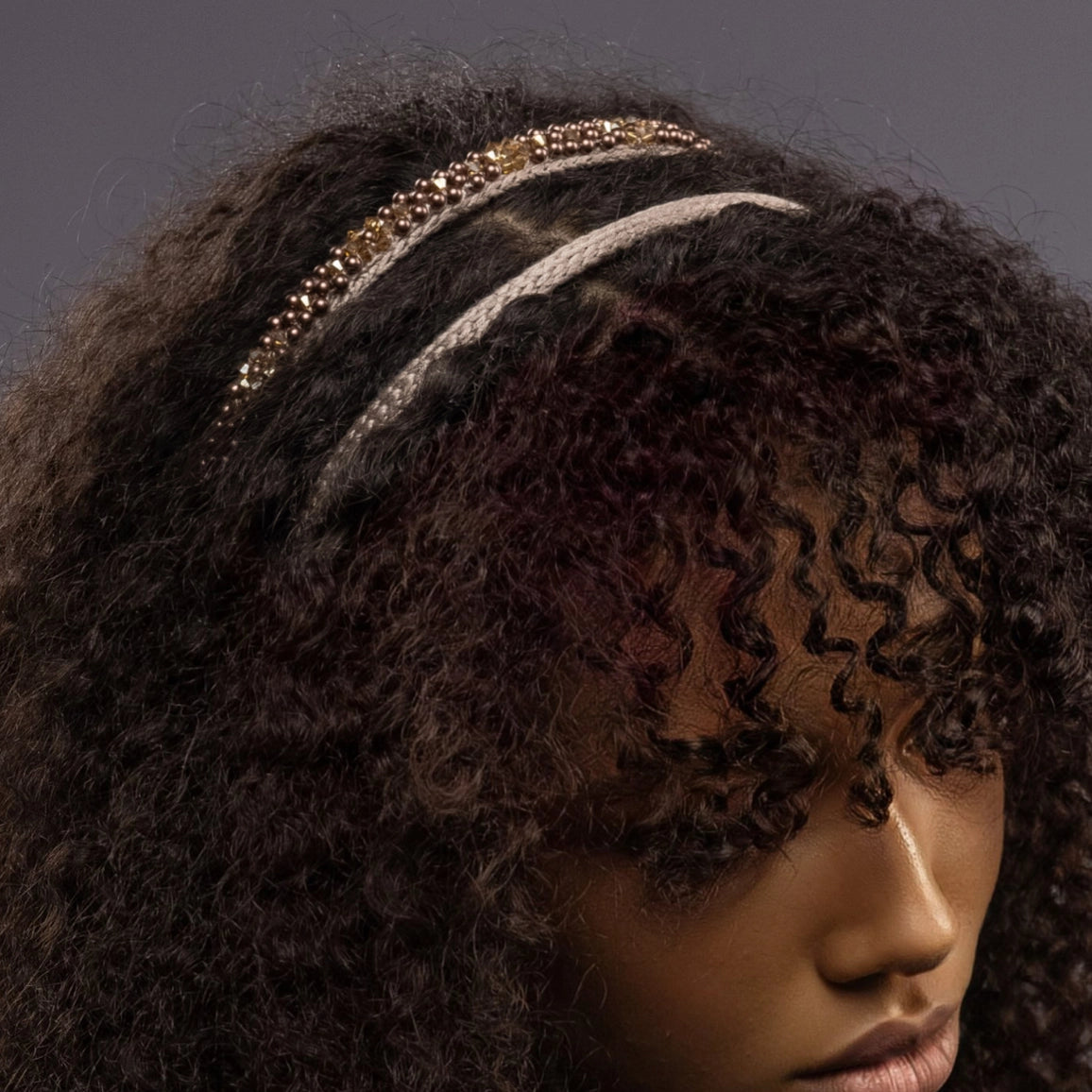 
                  
                    A dark-haired African woman is wearing Malkiele designer beige silk knit headbands, embellished with pearls from Swarovski, details, name Victorious.
                  
                