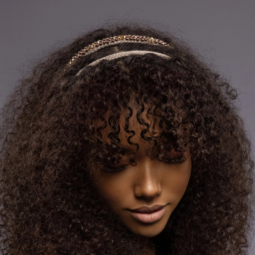 
                  
                    A dark-haired African woman is wearing Malkiele designer beige silk knit headbands, embellished with pearls from Swarovski, details, name Victorious.
                  
                