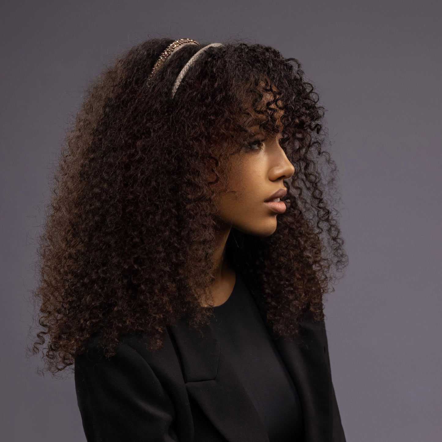 
                  
                    A dark-haired African woman is wearing Malkiele designer beige silk knit headbands, embellished with pearls from Swarovski, name Victorious.
                  
                