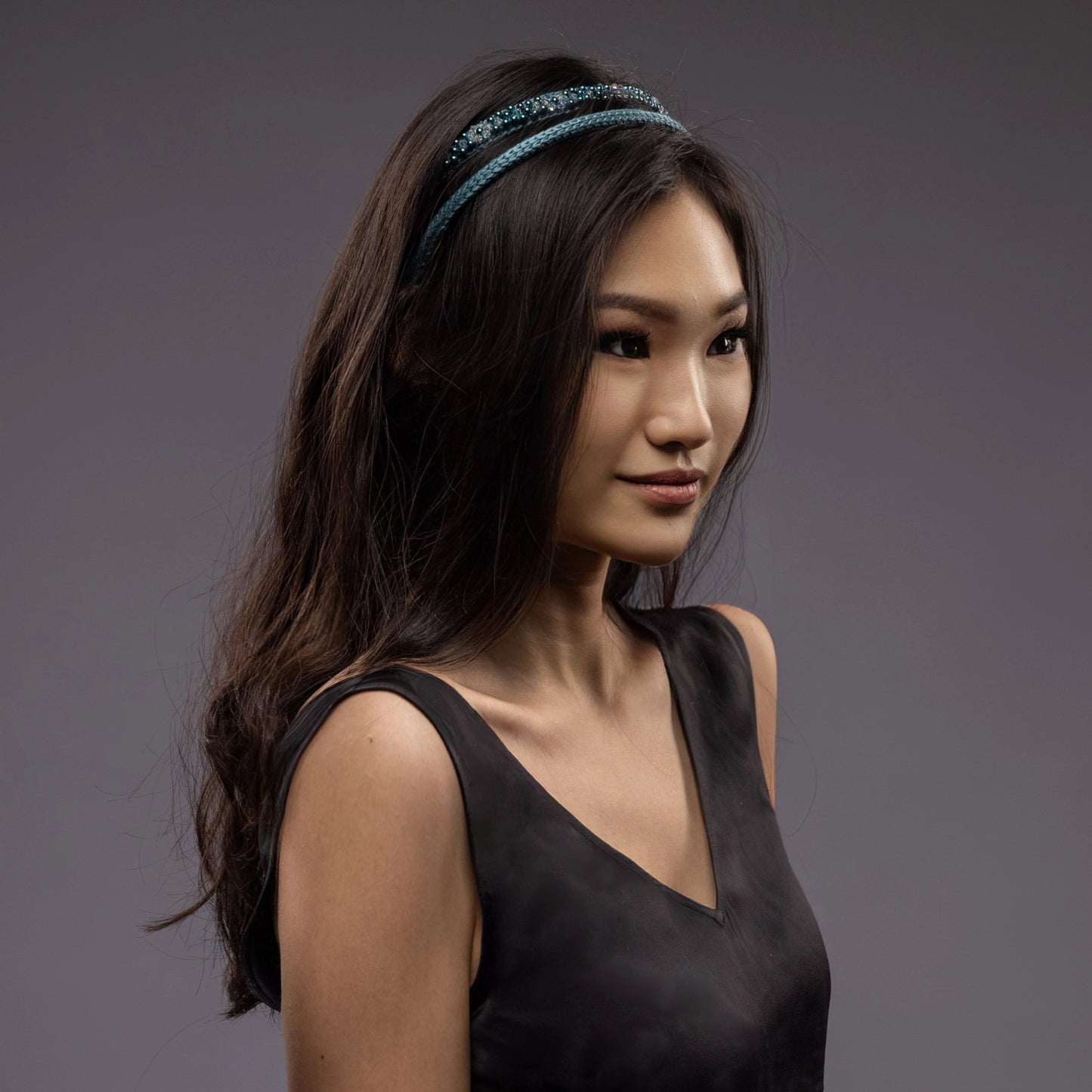 
                  
                    A dark-haired Asian girl is wearing Malkiele designer green silk knit headbands, embellished with pearls from Swarovski, name Victorious.
                  
                