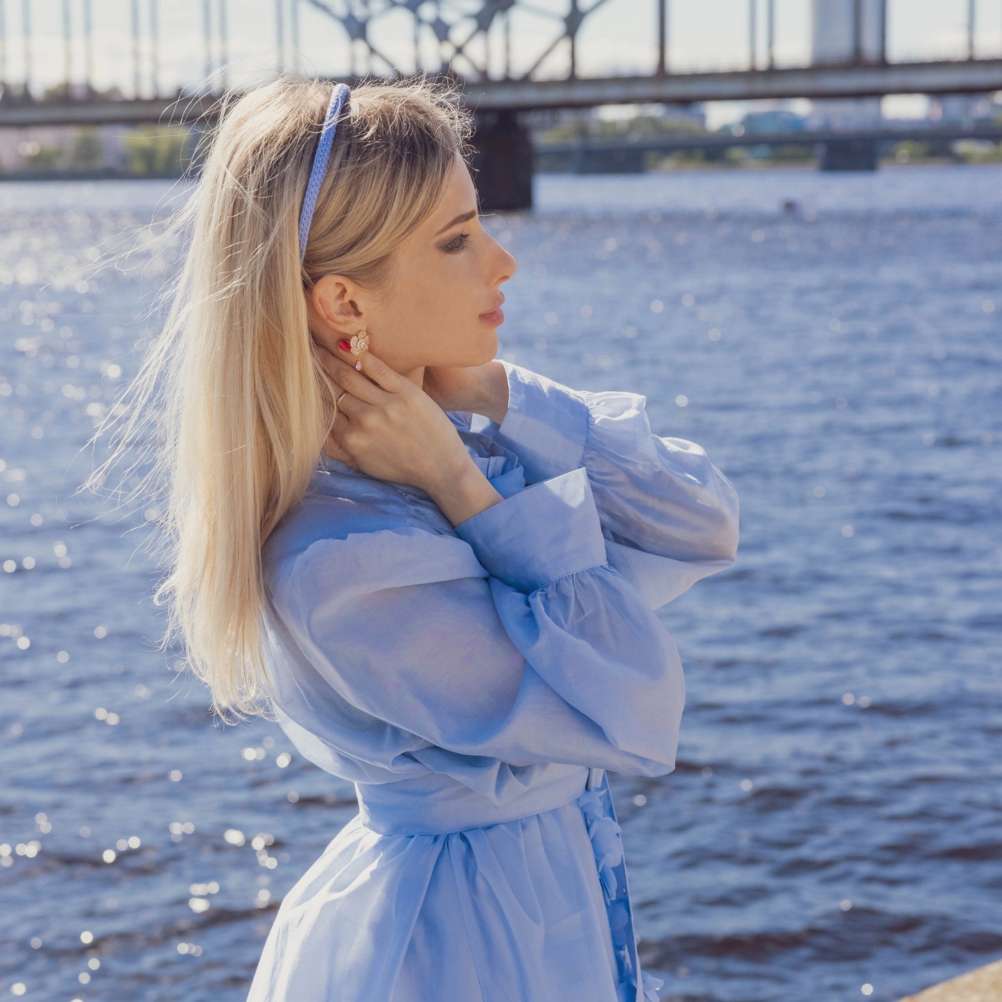 A blonde-haired girl in light blue dress is wearing Malkiele designer light blue silk knit headband, name Virgin.