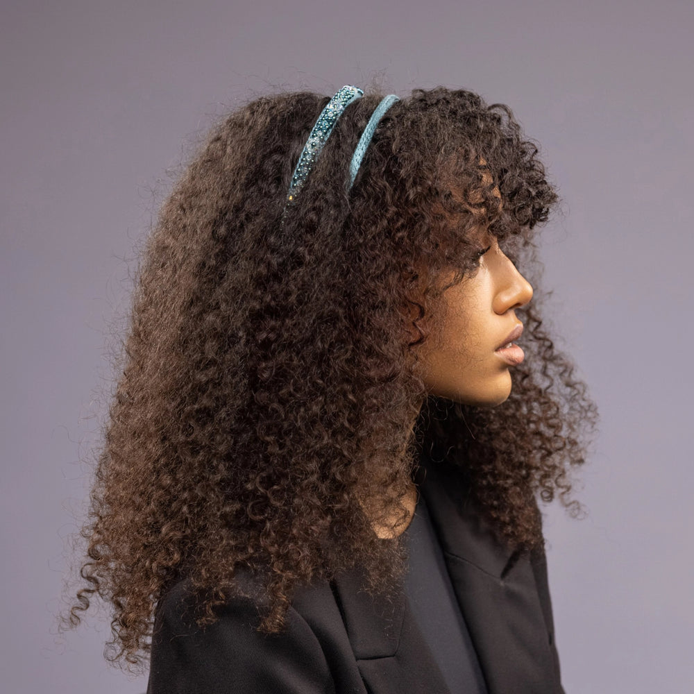 
                  
                    A dark-haired African woman is wearing Malkiele silk knit headband in green, name Virgin
                  
                