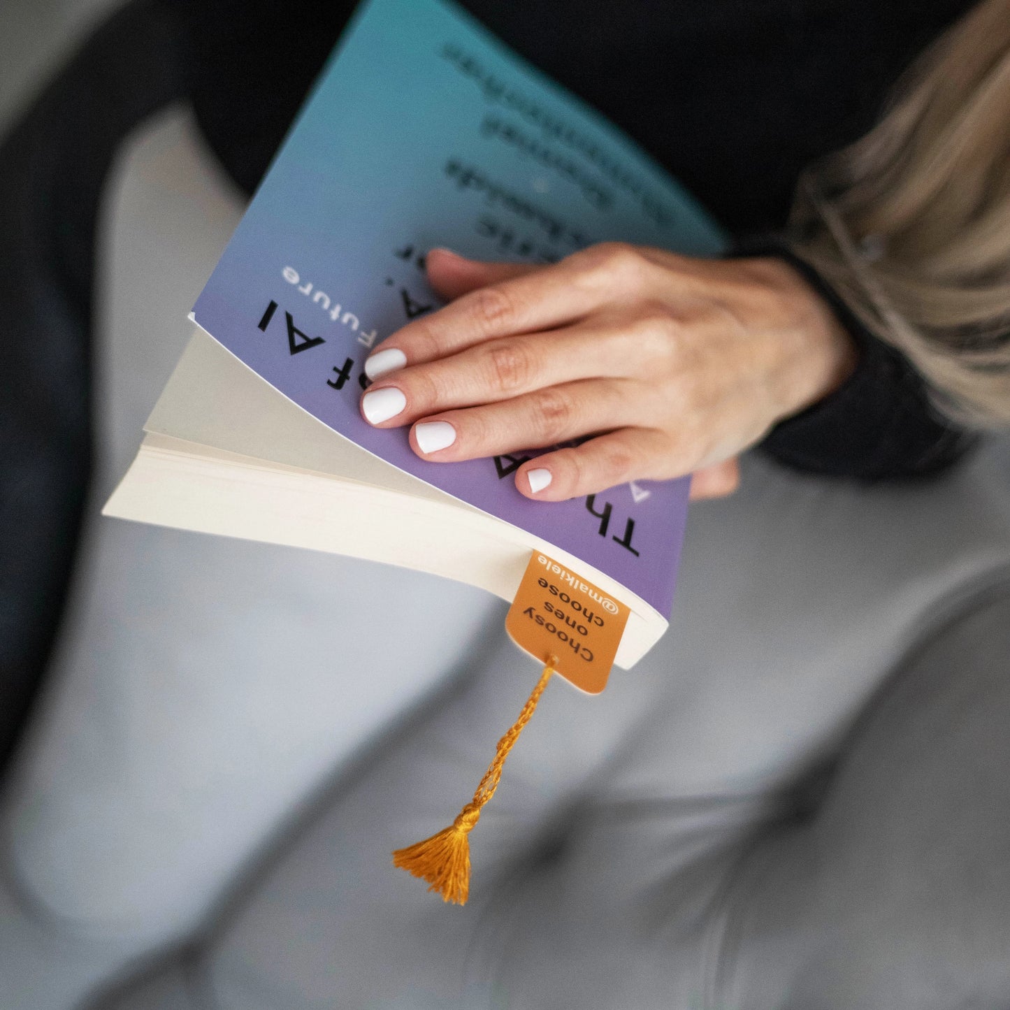 
                  
                    Woman’s hands are holding a book with Malkiele designer Bookmark with yellow silk tassel, name Witty.
                  
                